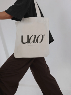Minimal canvas tote bag mockup with logo print, worn by model in neutral studio setting